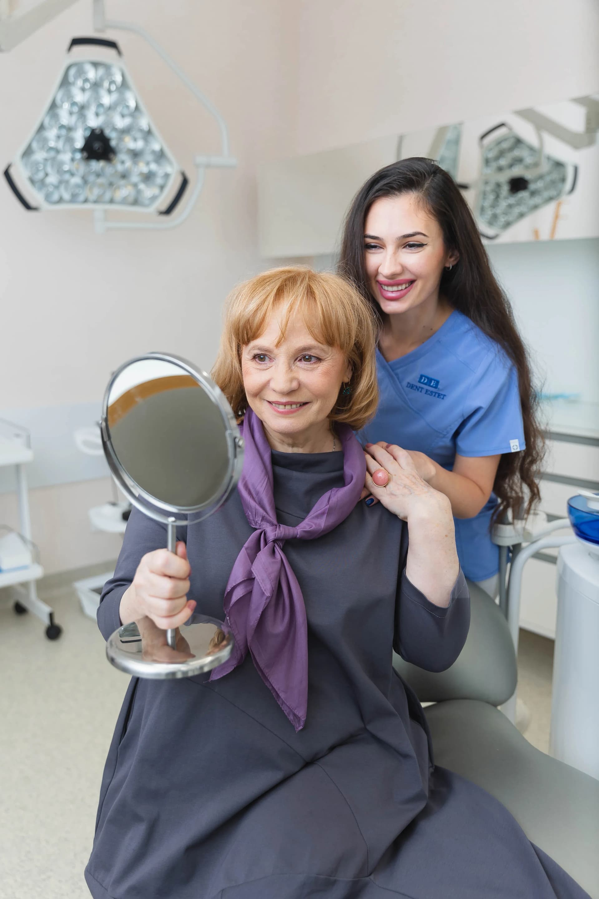 Pacientă zâmbește alături de medicul ei stomatolog, după tratamentul cu coroane dentare.
