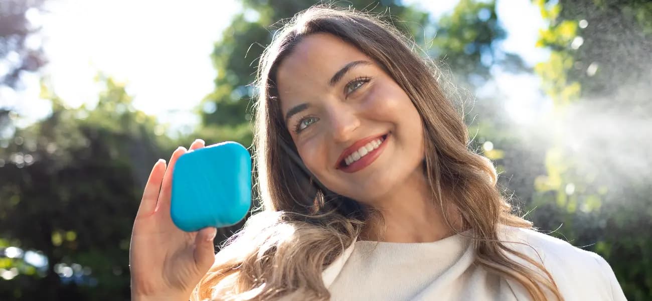 Smiling patient in outdoor setting holding a Spark aligners case.
