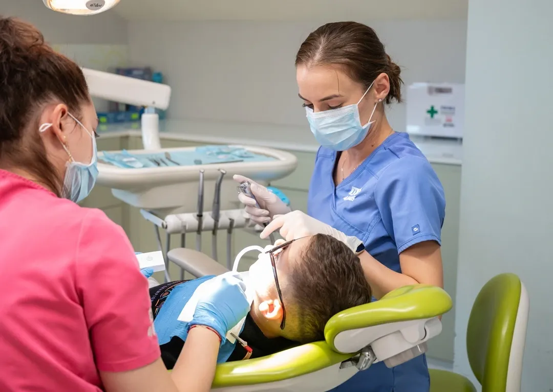 Medic stomatolog pediatru cu pacient copil in cabinetul stomatologic