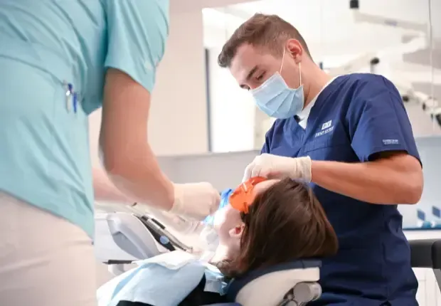 Endodntist Dr. Ștefan Zgîmbău applying rubber dental dam before root canal.