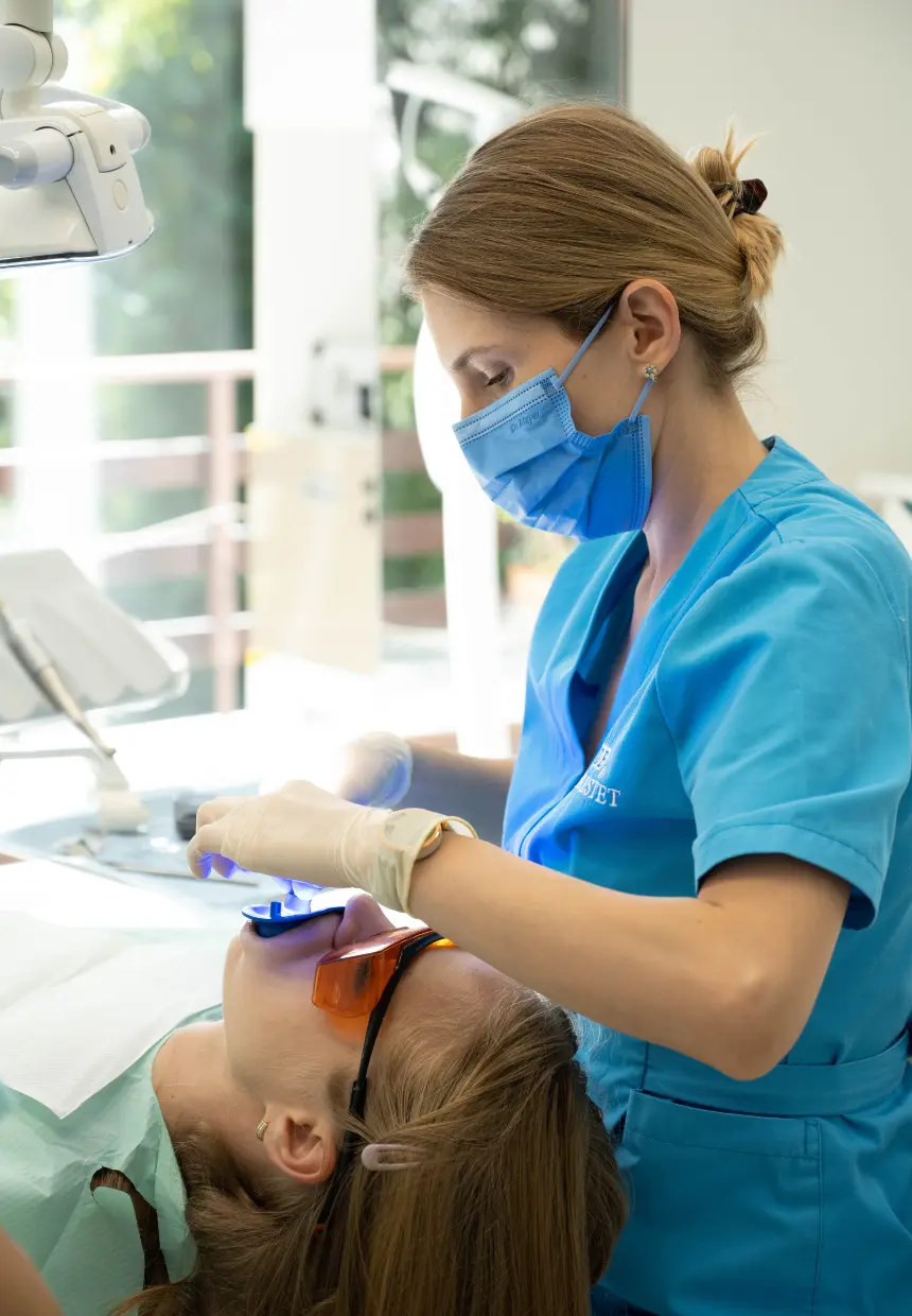 Medicul stomatolog pregătește pacienta pentru albire dentară profesională.