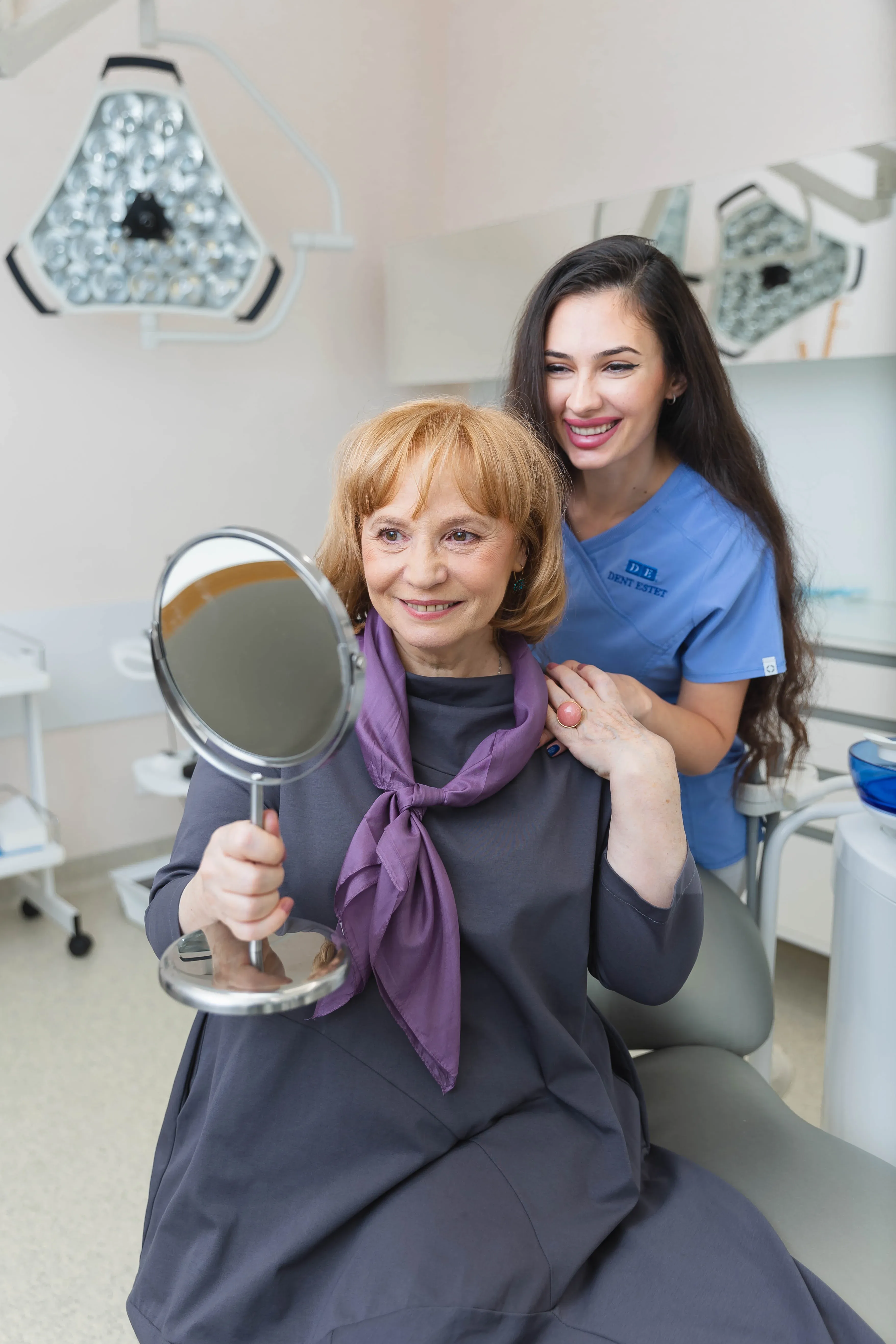 Pacientă zâmbește alături de medicul ei stomatolog, după tratamentul cu coroane dentare. 