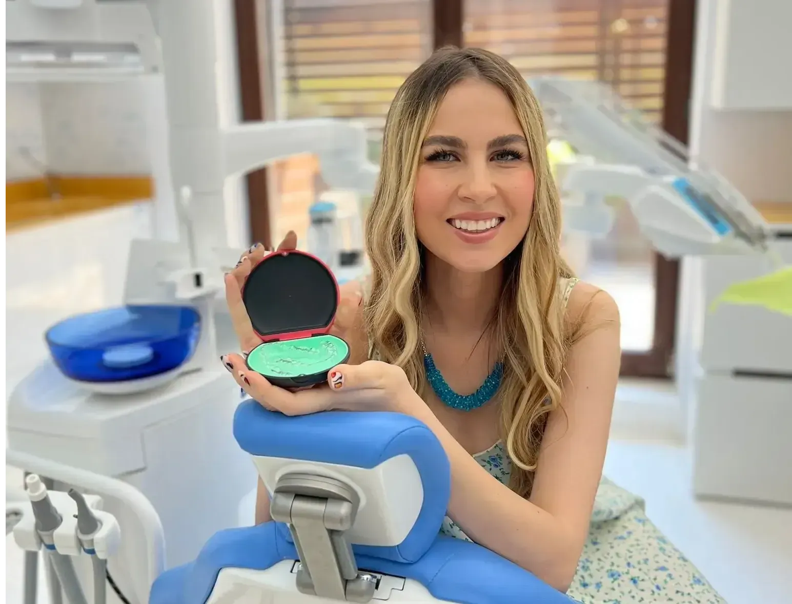 Patient smiling on dental chair holding clear aligner case